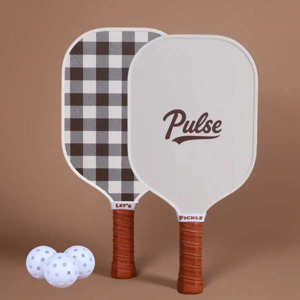 Two_pickleball_paddles_with_checkered_design_and_Pulse_branding_accompanied_by_three_white_balls_on_a_brown_background. - Pulse Pickleball