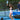 Woman playing pickleball on a blue outdoor court holding a Pulse Pickleball paddle with geometric design, smiling and enjoying a social game with Pulse branding visible in the background.”